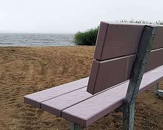 Eine Bank am Strand mit Blick auf einen See und Regen.